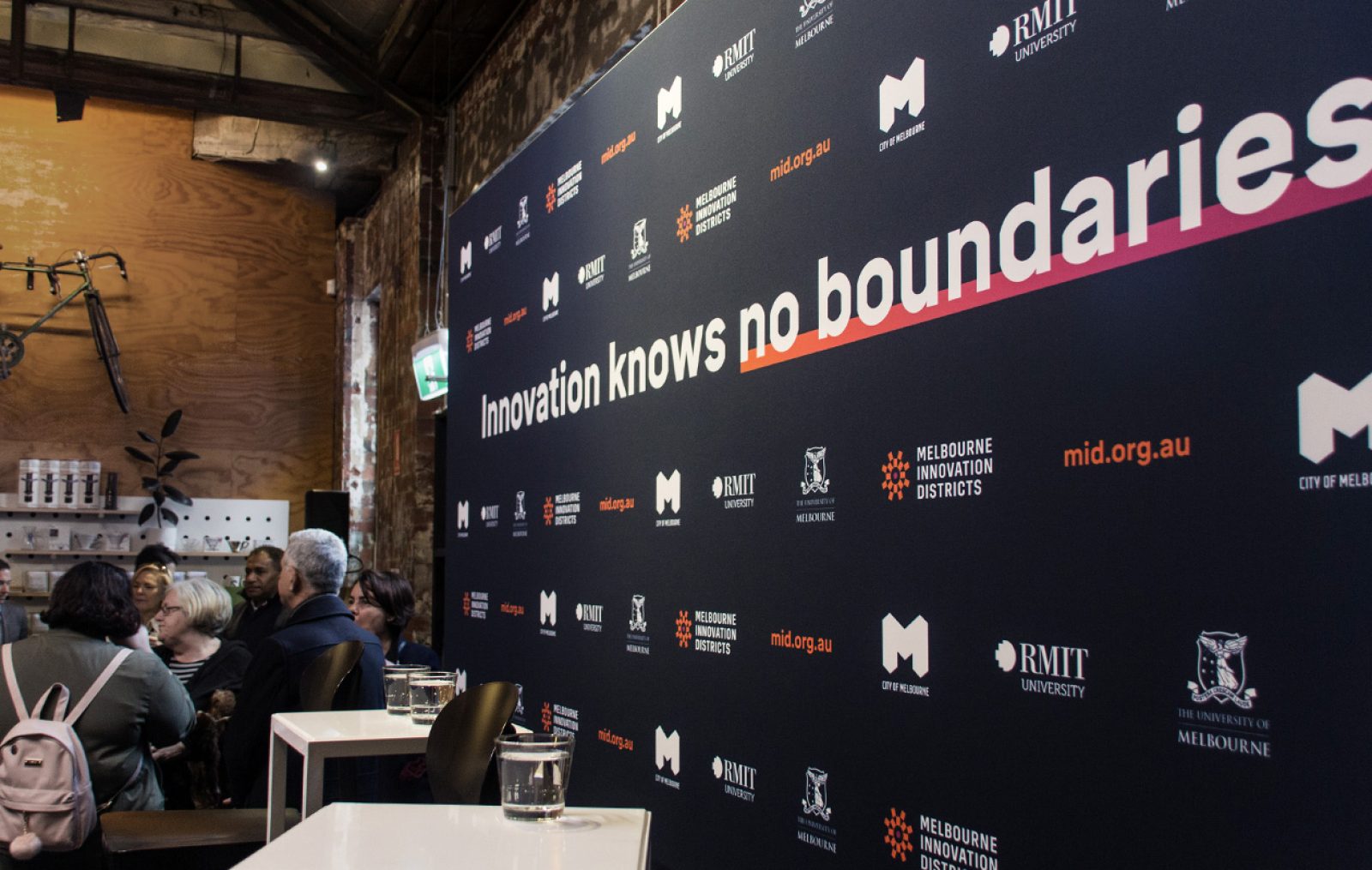 A co-branded media wall with the headline "Innovation Knows no Boundaries" and the logos of the MID, the City of Melbourne, RMIT University and the University of Melbourne