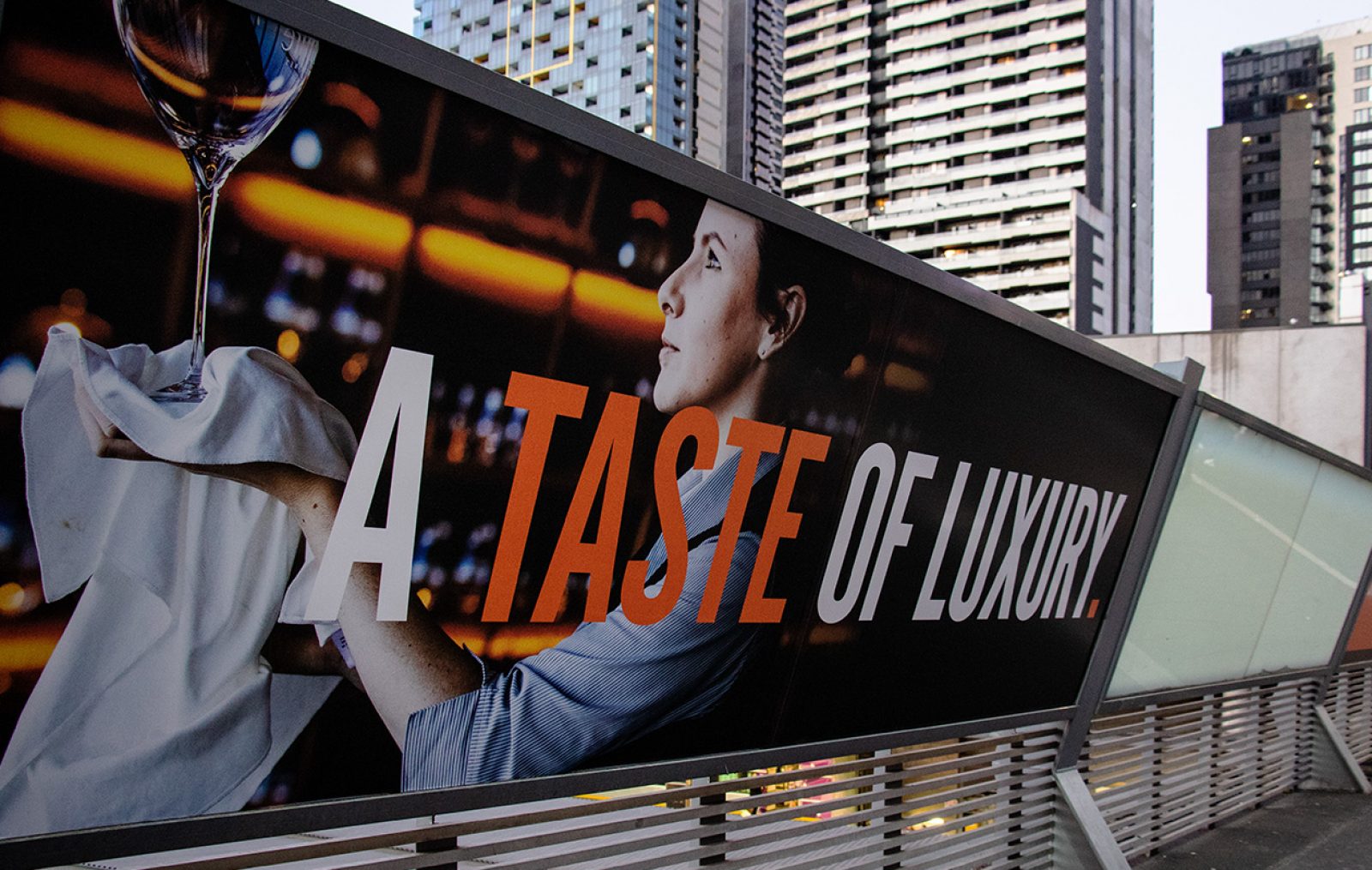 Billboard advertising at a train station with the tagline "A Taste of Luxury"