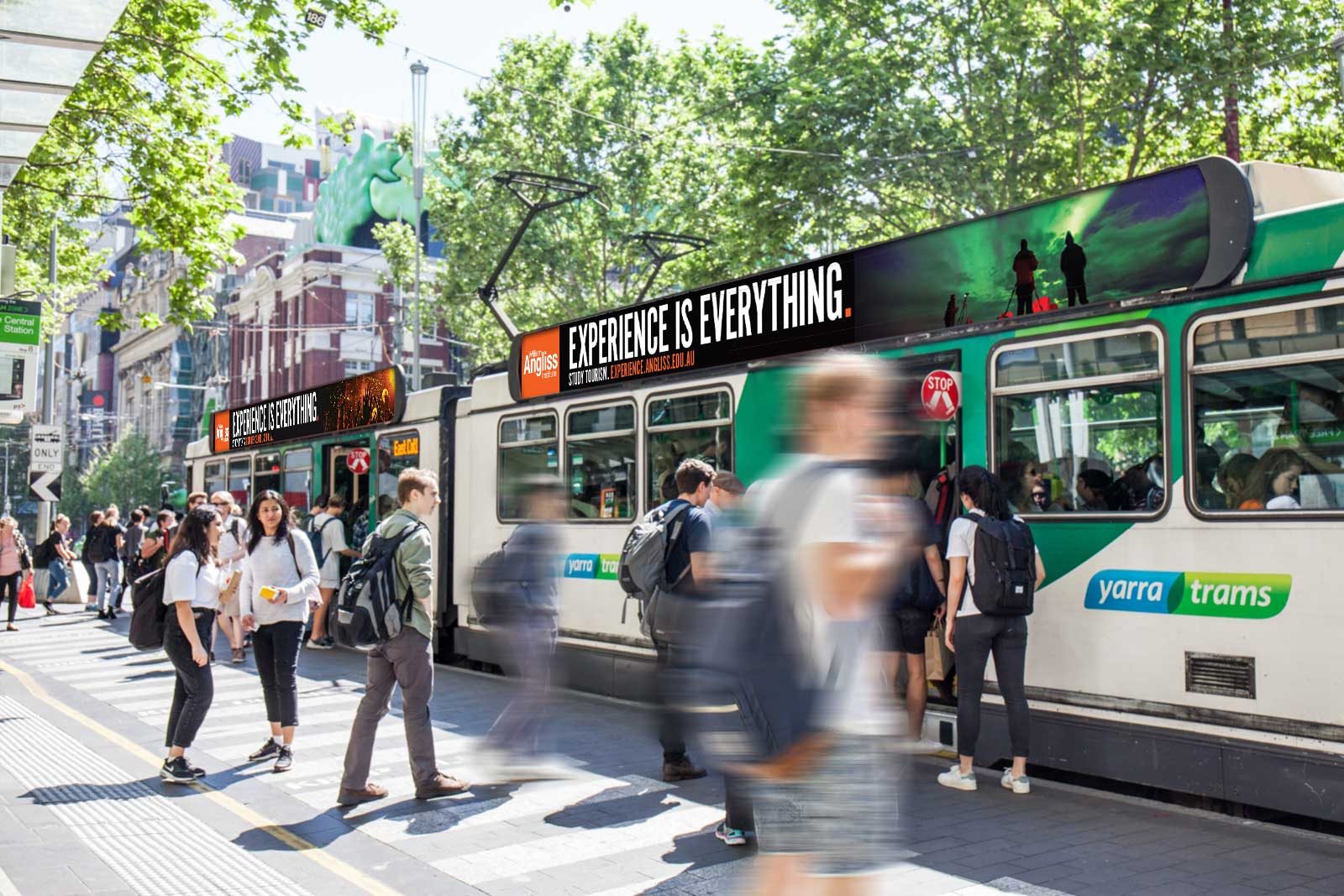 Melbourne trams at a tramstop featuring advertising with the headlines 'Experience is Everything'