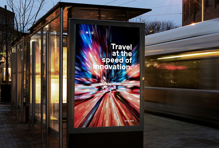 A backlit poster on bus stop advertising promoting the Melbourne Innovation Districts with the headline "Travel at the speed of innovation".